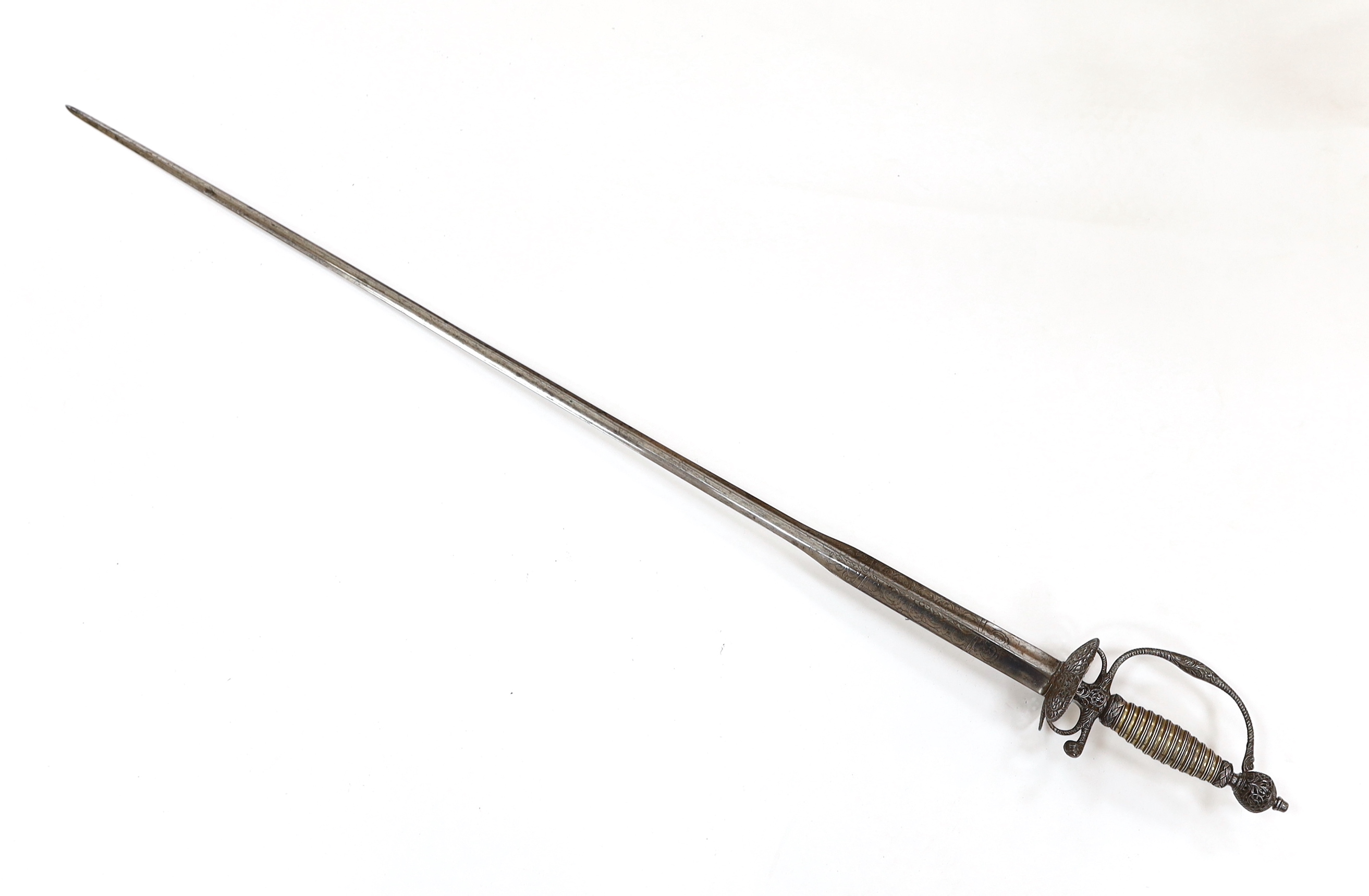 An English iron hilted small sword, c.1765, chiselled and pierced with scrolling devices and foliage, silver gilt tape and silver wire bound grip, colichemarde blade etched with scrolls and squirrel, blade 81.5cm